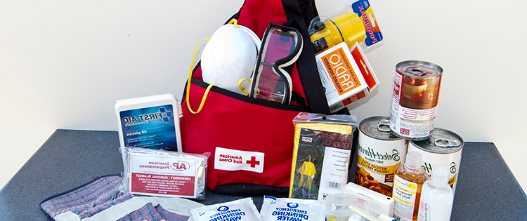 A red backpac with packaged food and water, safety glasses, dust mask, and first aid supplies.